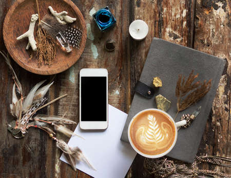 Rustic wooden background with boho chic style decorations: dreamctcher, cup of cappuccino, notebook and paper stars. Copy space for text. Natural, rustic, ethnic or hipster vintage mock up. Top view.の写真素材