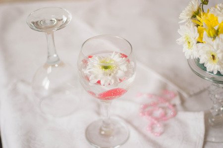 White Chrysanthemum in a glass with water and bubbles. At the bottom of a glass of red hearts.の写真素材