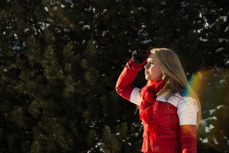 young blond woman in forest looking at the horizon at winterの写真素材