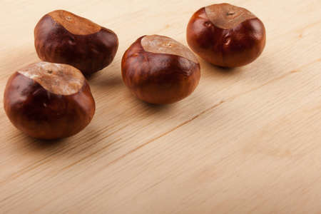 Four chestnut fruit on a wooden tableの写真素材
