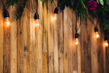 Wedding background of boards, decorated with light bulbs and flowers.の写真素材
