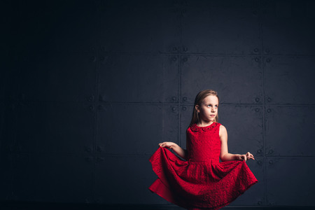 girl in red dress in studio on dark background. Copy spaceの写真素材