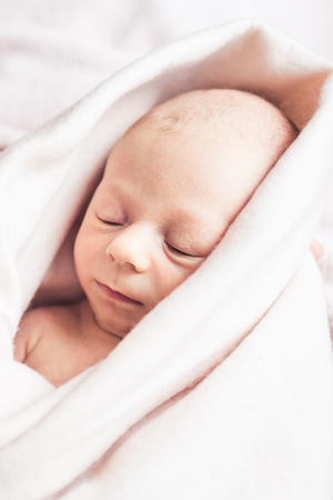 Newborn baby sleeps wrapped in blanket.の写真素材