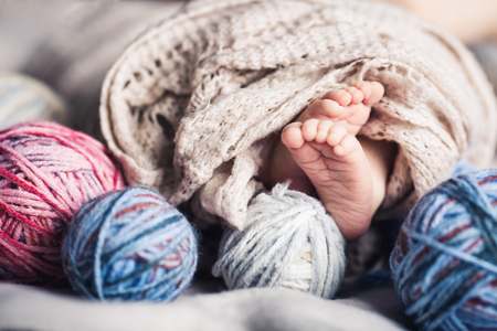 Baby's legs look out from under blankets among tangles of thread. Beautiful concept of childhood.の写真素材