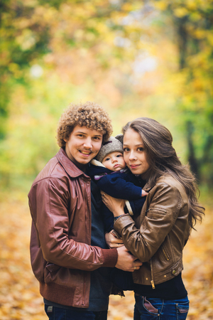 Young family hugging in autumn in parkの写真素材