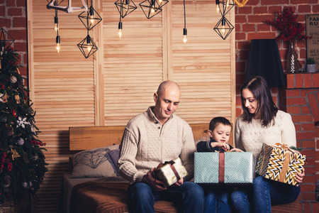 father, mother and son sitting on the couch and looking at their Christmas presentsの写真素材
