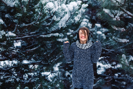 Stylish cheerful girl in a sweater in the winter forestの写真素材