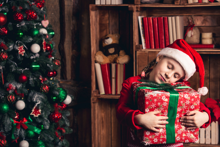 Happy girl with affection holds a Christmas gift in her handsの写真素材