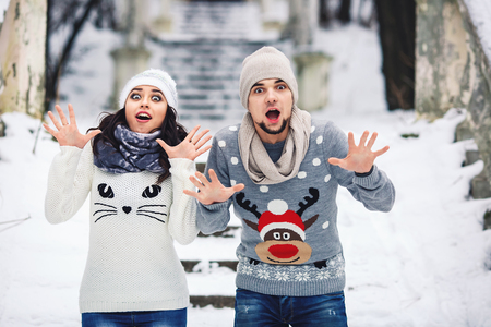 young couple in love having fun on a winter walk. man and woman show emotions: wow, shock, surprise, fear, scareの写真素材