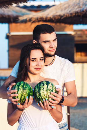 boy and girl stand on the beach and hold watermelonsの写真素材