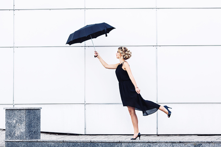 Beautiful girl with umbrella blows the windの写真素材