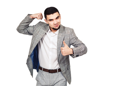 self-confident businessman. Stylish young bearded guy in a gray suit shows his biceps. isolated on whiteの写真素材