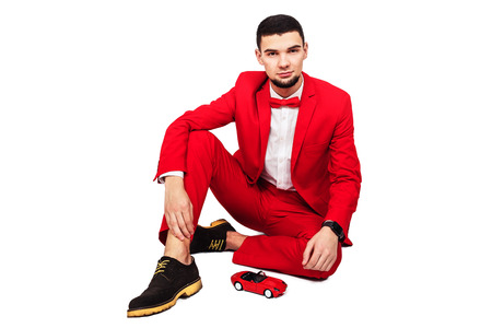 man wants to buy a car. bearded man in a red suit and red toy car on a white background.の写真素材