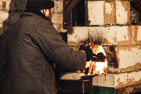 Bearded blacksmith throws coal into the furnaceの写真素材