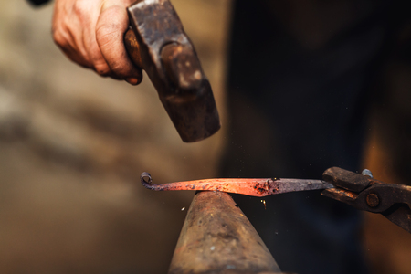 blacksmith makes an artistic forging of hot metal on the anvil