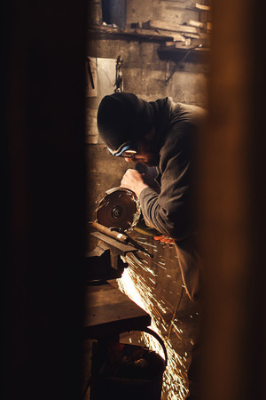 worker in the workshop cuts a metal blank a grinderの写真素材