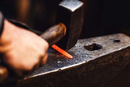 blacksmith makes an artistic forging of hot metal on the anvilの写真素材