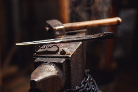 closeup of a blacksmith anvil with a hammer, tongs, firesteel and flintの写真素材