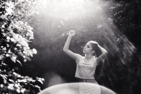 Wonderful spring. A beautiful young girl enjoys nature and sunlight among the blossoming lilacの写真素材