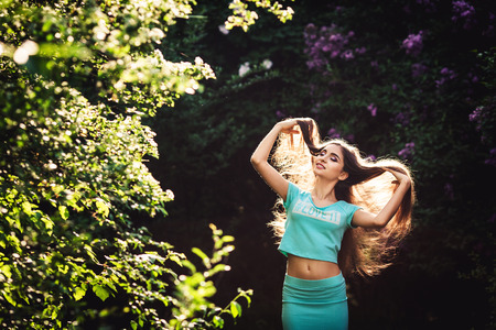 Wonderful spring. A beautiful young girl enjoys nature and sunlight among the blossoming lilacの写真素材