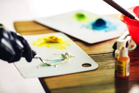 pastry chef in black rubber gloves stirs colored cream with spatula to decorate cake. food coloring for cream.の写真素材