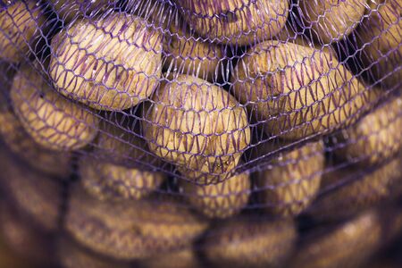 Close-up of potato tubers in mesh bag. autumn harvest concept.の写真素材