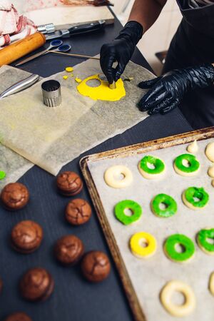 pastry chef decorates raw profiteroles with green and yellow shortcrust pastry