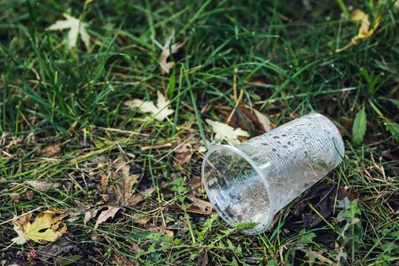 plastic glasses are lying on the grass. Environmental pollution concept.の写真素材