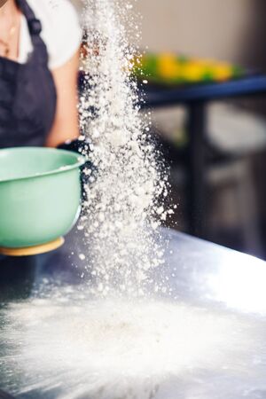the baker sprinkles flour on top of the tableの写真素材
