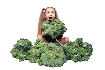 little girl holds and bites big broccoli. isolated on white. nutrition and healthy eating habits for kids concept. child athlete veganの写真素材