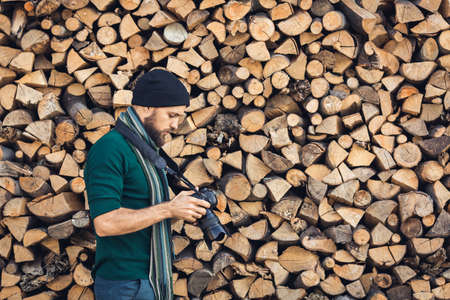 bearded photographer in nature with digital camera on firewood wall backgroundの写真素材