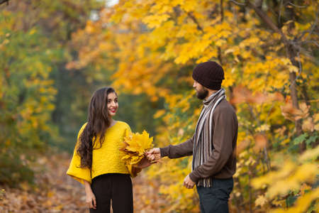 Happy couple in the autumn park. Young family having fun outdoors.の写真素材
