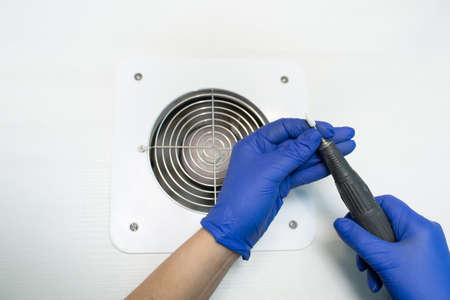 Drill for nails. A gloved manicurist inserts a nail cutter into the drill.の写真素材