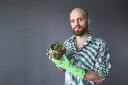 Florarium Glass vase with succulent. bearded man shows a vase with succulents and moss.