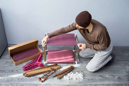 Bearded man assembles a shelf for the rackの写真素材