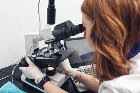 female laboratory assistant examines with a microscope in a chemical laboratory.の写真素材