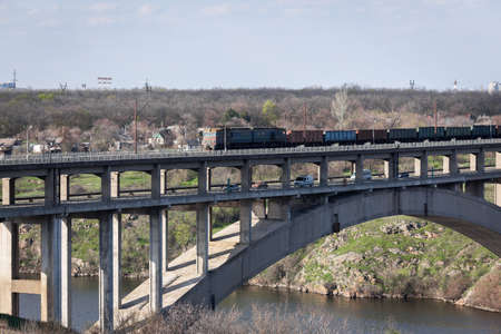 View of the reinforced concrete two-level arched bridge. Freight train rides across the bridge.の写真素材