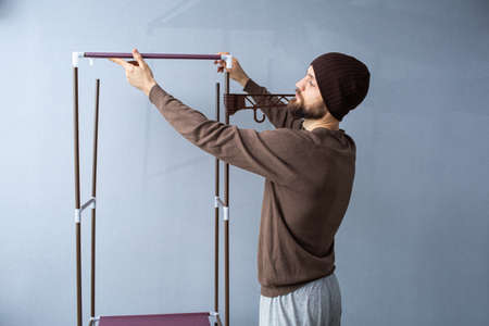Bearded man assembles a shelf for the rack.