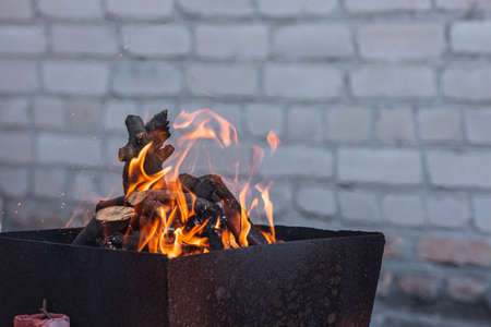 burning firewood in the grill on the background of a brick wall