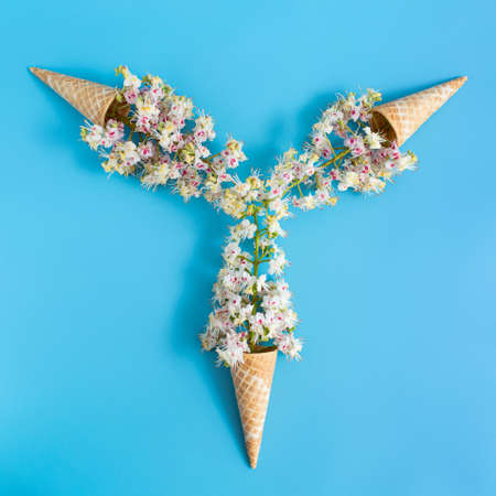 Three sweet crispy wafer cups with chestnut flowers on a blue backgroundの写真素材