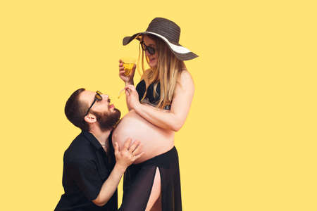 bearded man hugging belly of pregnant wife on isolated yellow background. The concept of the...