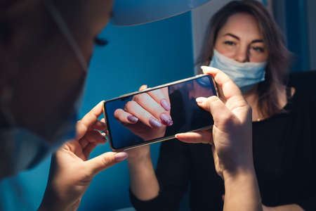 Manicurist photographs clients nails with a smartphone