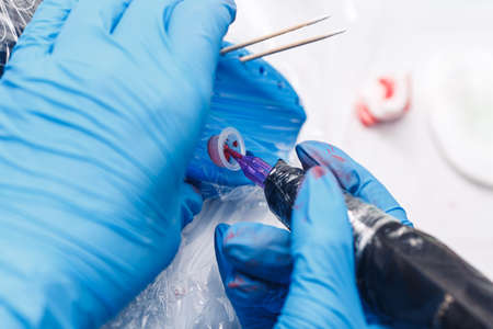 beautician takes pigment for tattoo. Permanent makeup machine