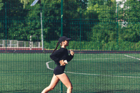 Morning run at the stadium. The girl with the phone goes in for sports.の写真素材