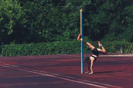 girl does exercises on the sports ground. Handstand, warm-up before training.の写真素材