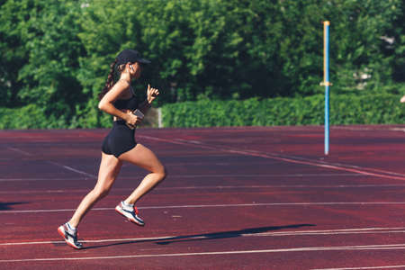 Morning run at the stadium. The girl with the phone goes in for sports.の写真素材
