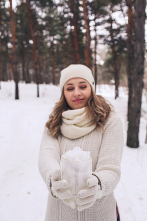 Cheerful girl holding snow in a cup. merry christmas and happy new year.