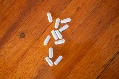 Drug pills in various shape and sizes on wooded table, space for text