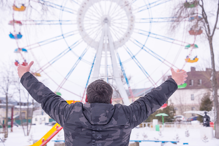 Man raises his hands, looks at the Ferris wheelの写真素材