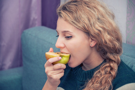 young girl eating an Apple, ripe Apple , eats , the girl with the braidsの写真素材